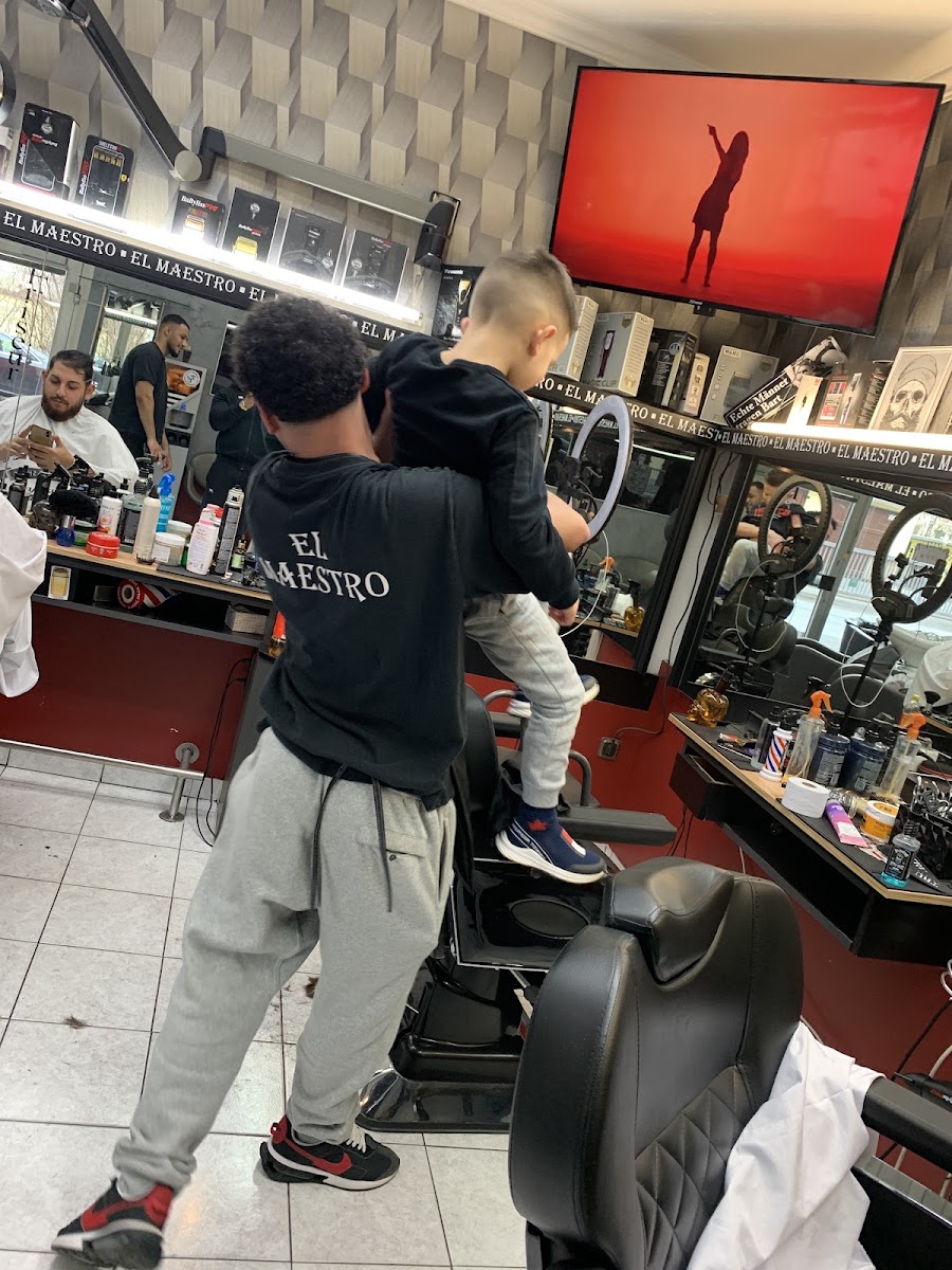Barbier trägt ein Kind für den Kinderhaarschnitt zum Stuhl